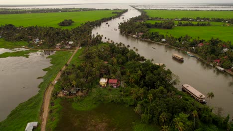 Drone-ascent-revealing-houseboats-sailing-river-in-Kumarakom,-Kerala,-India
