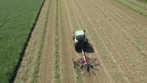 On-a-farm-field-in-southwest-Wisconsin,-a-farmer-rakes-hay-using-a-rotary-hay-rake-6