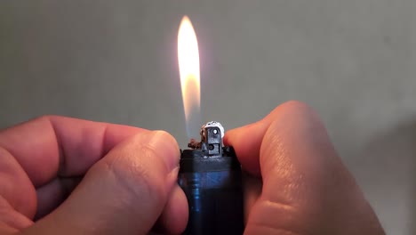 4k-Video-of-hands-holding-a-blue-lighter-and-adjusting-the-flame-with-the-fingers-by-sliding-the-lever-which-controls-the-butane-gas-levels