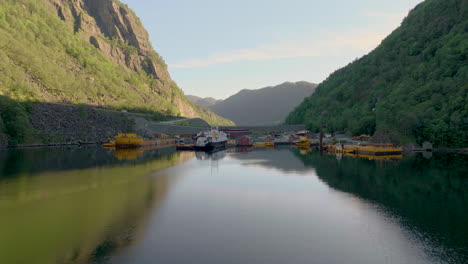 Drone-Flying-Towards-Industrial-Harbour-On-Fjord-With-Ferry-And-Other-Marine-Vessels-Moored