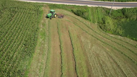 On-a-farm-field-in-southwest-Wisconsin,-a-farmer-rakes-hay-using-a-rotary-hay-rake-4