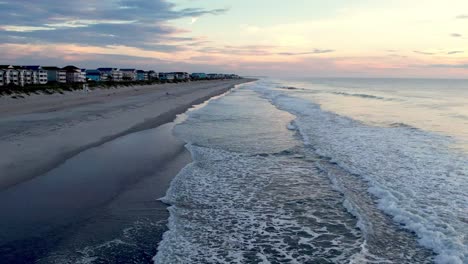 Low-aerial-over-surf-and-waves-rolling-into-carolina-beach-nc,-north-carolina-at-sunrise