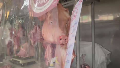 Vídeo-De-4k-De-La-Cabeza-De-Un-Cerdo-Detrás-De-Una-Película-De-Plástico-En-El-Mercado-De-La-Carne