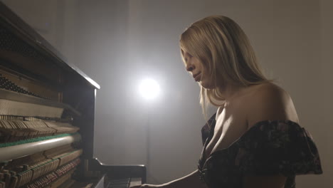 Woman-playing-upright-piano-with-open-sound-board-showing-hammers-striking-the-strings-1