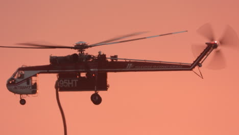 In-glowing-red-sky-an-Elvis-water-bombing-helicopter-descends-to-refill-tanks