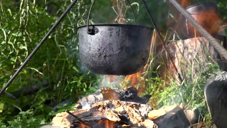 Cooking-food-at-a-campfire-with-a-metal-pot-in-the-wild,-camping-concept-background-with-no-people