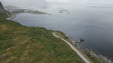 Aufsteigende-Filmische-Bewegung,-Die-Die-Norwegische-Landschaft-Auf-Den-Lofoten-Mit-Blick-Auf-Reine-Mit-Bergen-Und-Fjord-Und-Meer-Im-Hintergrund-Zeigt