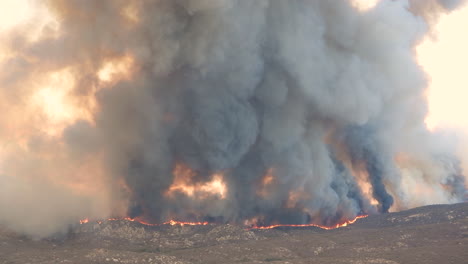 Aerial-view-of-firefighting-plane-flying-over-burning-wildfire-with-dark-smoke-in-California---Environmental-pollution-during-heat-and-climate-change