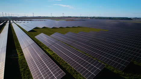 Drone-rising,-reveals-solar-panel-farm-with-wind-mills