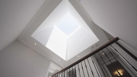 Pan-and-tilt-shot-from-staircase-to-the-flat-roof-window-on-the-ceiling-in-a-house-during-a-sunny-day