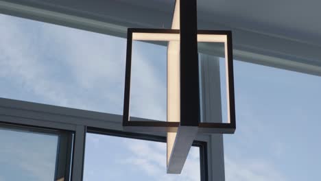 Close-up-dolly-detail-shot-of-a-contemporary-pendant-lamp-with-ceiling-high-window-at-the-back-in-a-condominium-during-a-sunny-day