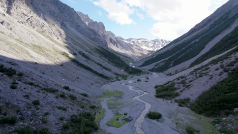 Luftdrohnenaufnahmen,-Die-Langsam-Nach-Links-Durch-Ein-Dramatisches-Gletschertal-Rollen,-Umgeben-Von-Steilen-Bergen-Und-Kiefern-Mit-Schneeflecken-Und-Einem-Alpenfluss-In-Der-Schweiz