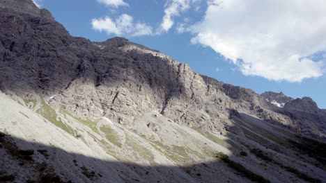 Aerial-drone-footage-slowly-twisting-to-reveal-a-spiny-ridge-and-mountain-summits-at-the-top-of-imposing-cliffs-in-a-glacial-valley-in-Switzerland