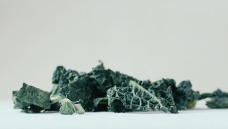 Rain-of-pieces-of-kale-leaves-fall-in-slow-motion,-natural-light