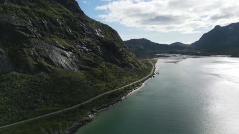 Aerial-view-showing-a-fjord-in-Lofoten-Norway-along-which-a-road-runs-with-mountains-in-all-directions