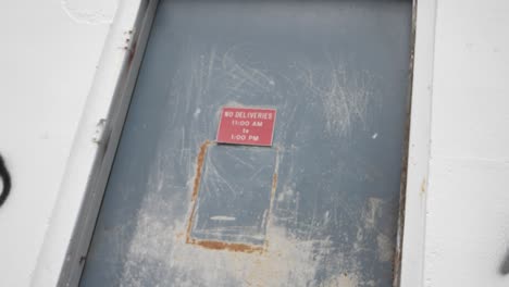Slow-Motion-Push-In-On-A-Creepy-Red-No-Deliveries-Sign-On-an-Abandoned-Warehouse-Door