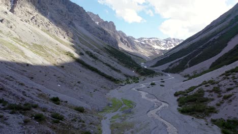 Aerial-drone-footage-flying-through-a-dramatic-glacial-valley-surrounded-by-a-steep-mountains-and-pine-trees-with-patches-of-snow-and-an-alpine-river-in-Switzerland