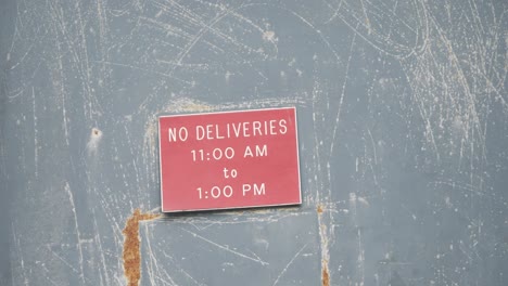 Slow-Motion-Pan-Across-A-Creepy-Red-No-Deliveries-Sign-On-an-Abandoned-Warehouse-Door