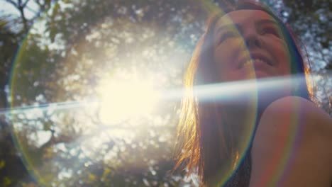 Smiling-middle-aged-hispanic-woman-looking-over-the-shoulder,-low-angle-with-lens-flare