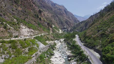 Drone-Shot-of-a-small-road-and-river-in-Himachal-Pradesh-near-Manali,-Kasol