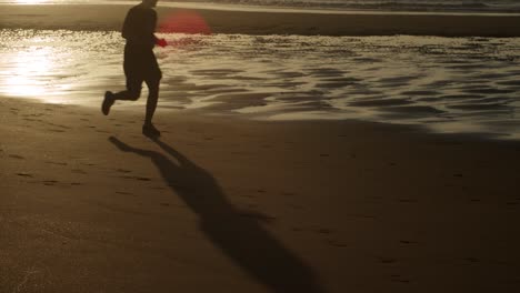 Silhouette-Und-Schatten-Des-Mannes,-Der-Bei-Sonnenuntergang-Mit-Am-Strand-Läuft