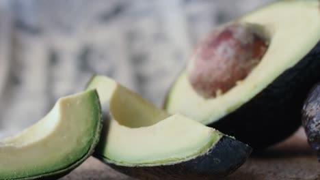 Pieces-of-avocado-are-dropped-on-a-wooden-board,-the-other-half-of-the-fruit-is-placed-on-the-table