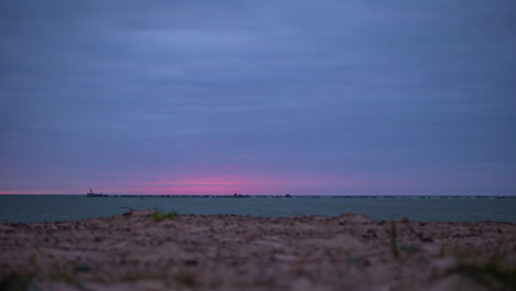Timelapse-shot-of-blue-and-red-sky-over-the-sea-just-after-sunset-along-the-shoreline-during-evening-time