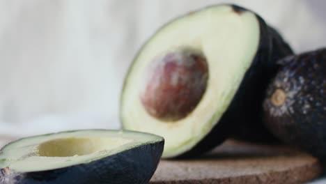 An-avocado-is-cut-in-two-and-one-half-falls-in-slow-motion-on-the-table-revealing-the-inside-and-the-pit