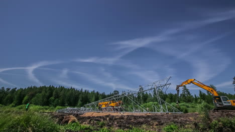 Erecting-a-powerline-tower-pylon-in-rural-Europe-using-crane,-excavator-and-other-heavy-equipment---construction-time-lapse