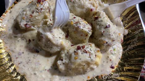 A-man-holding-a-platter-of-Afghani-Momo-served-with-creamy-white-sauce-or-Béchamel-sauce-sold-in-Kolkata