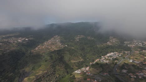 Aerial-view-of-the-Calheta-parish-in-the-Madeira-Island,-Drone-moving-forward-in-direction-of-the-houses-on-the-top-of-the-mountain