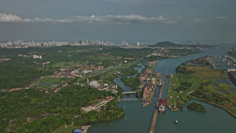 Panama-City-Aerial-v38-descending-flyover-miraflores-lake-capturing-cargo-ships-transiting-at-locks-canal-with-cityscape-in-distance-background-along-skyline---Shot-with-Mavic-3-Cine---March-2022