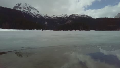 Panning-footage-of-the-Black-lake-Crno-Jezero-with-snow-capped-mountains-of-Durmitor-in-the-backdrop,-Albania