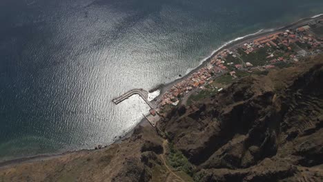 Aerial-view-of-the-Calheta-parish-in-the-Madeira-Island,-Drone-rotating-showing-the-the-showing-the-contrast-between-the-village-near-the-sea-and-the-mountains-in-the-background-1