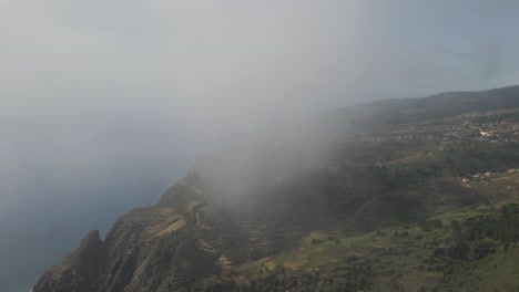 Vista-Aérea-De-La-Parroquia-Calheta-En-La-Isla-De-Madeira,-Algo-De-Niebla-Despejando-De-La-Cámara-Mostrando-Las-Montañas-Verdes-Y-El-Océano-Azul-1