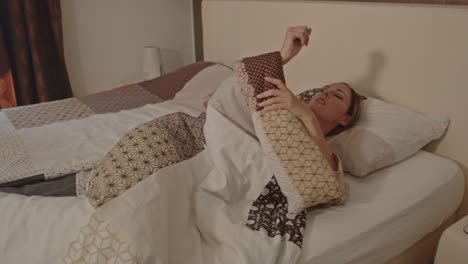 Woman-lying-in-her-bed-slowly-waking-up-in-luxurious-bedroom