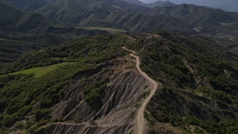 Drone-footage-of-winding-dirt-road-through-the-picturesque-Trebeshinë-Dhëmbel-Nemërçkë-mountain-chain-near-Permet,-Albania