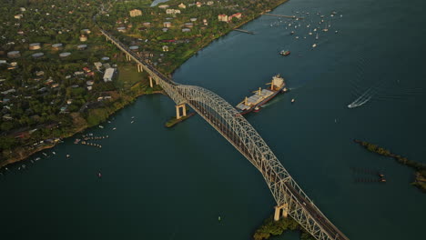 Panama-City-Aerial-v50-cinematic-birds-eye-view,-flyover-from-high-to-low-capturing-bridge-of-americas-with-cargo-ship-sailing-across-the-water-canal-at-sunset---Shot-with-Mavic-3-Cine---March-2022