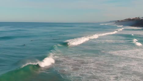 This-super-slow-motion-video-shows-a-group-of-surfers-in-the-ocean,-one-catching-and-riding-a-wave-1