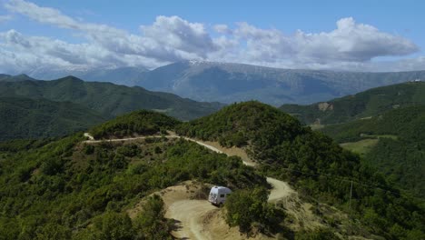 Imágenes-De-Drones-De-Una-Autocaravana-En-Un-Camino-De-Tierra-Ventoso-En-La-Cima-De-Las-Montañas-Cerca-De-Permet,-Albania