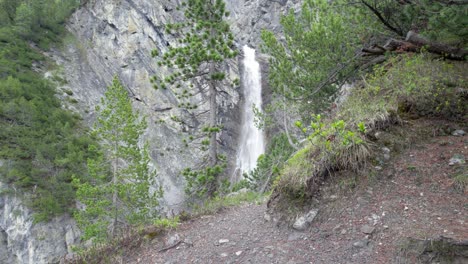 Luftdrohne-Schoss-Langsam-Nach-Links,-Um-Einen-Dramatischen-Wasserfall-Zu-Enthüllen,-Der-über-Den-Rand-Einer-Steilen-Bergklippe-In-Der-Schweiz-Stürzt,-Umgeben-Von-Kiefern
