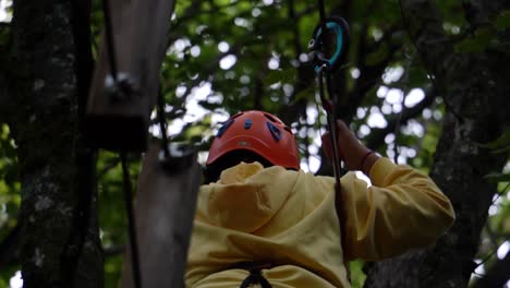 Brave-boy-goes-through-the-ropes-hanging-on-the-tree-with-the-safety-equipment-in-a-climbing-training