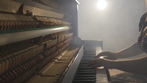 Sexy-woman-surrounded-by-smoke-playing-dramatic-music-on-vertical-piano-with-open-sound-board