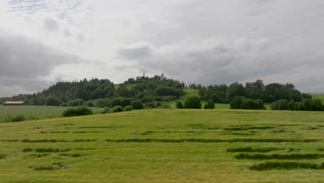 Grüne-Weizenfelder-Auf-Weitläufigem-Ackerland-Mit-Kirche-Auf-Einem-Hügel-Im-Fernen-Hintergrund