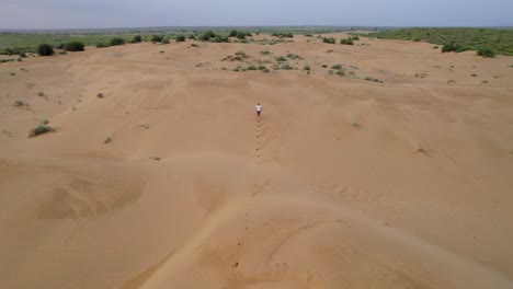 Drone-tracking-a-blonde-caucasian-girl-running-in-vast-desert-dunes