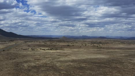 Aerial-slow-backwards-tracking-shot-of-a-moody-cloudy-desert-landscape-in-the-Karoo,-South-Africa