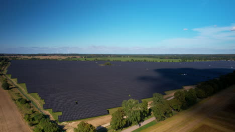 Drone-shot-showing-huge-solar-panels-farm-in-countryside-during-sunny-day-with-clear-blue-sky-outdoors