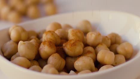 Curry-rain-falls-in-slow-motion-on-chickpeas-placed-in-a-white-bowl
