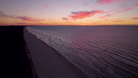 Aerial-view-of-beautiful-beach-in-Krynica-Morska-during-golden-sunset-at-horizon---Tranquil-waves-of-Baltic-Sea-reaching-shoreline