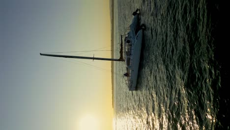 Vertical-Shot---Sailing-Catamaran-Yacht-On-The-Sea-With-Picturesque-Sunrise-In-The-Background